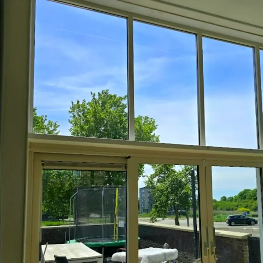 Woonkamer met een kunststof schuifpui als glaswand naar de tuin, in de zomer
